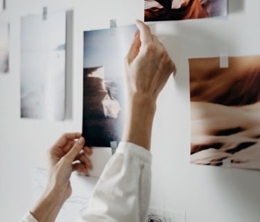 A pair of hands taping up pictures on a wall for inspiration.