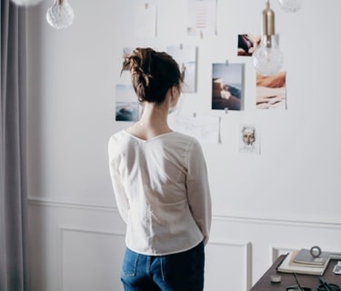 A woman standing in front of a wall of pictures gathering inspiration.