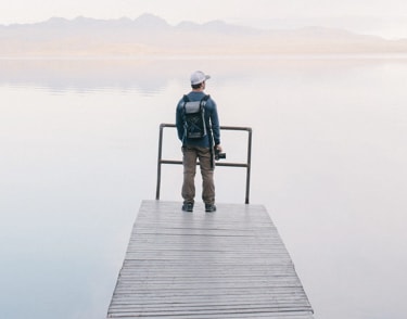 A man standing at the edge of a dock with a camera in hand.